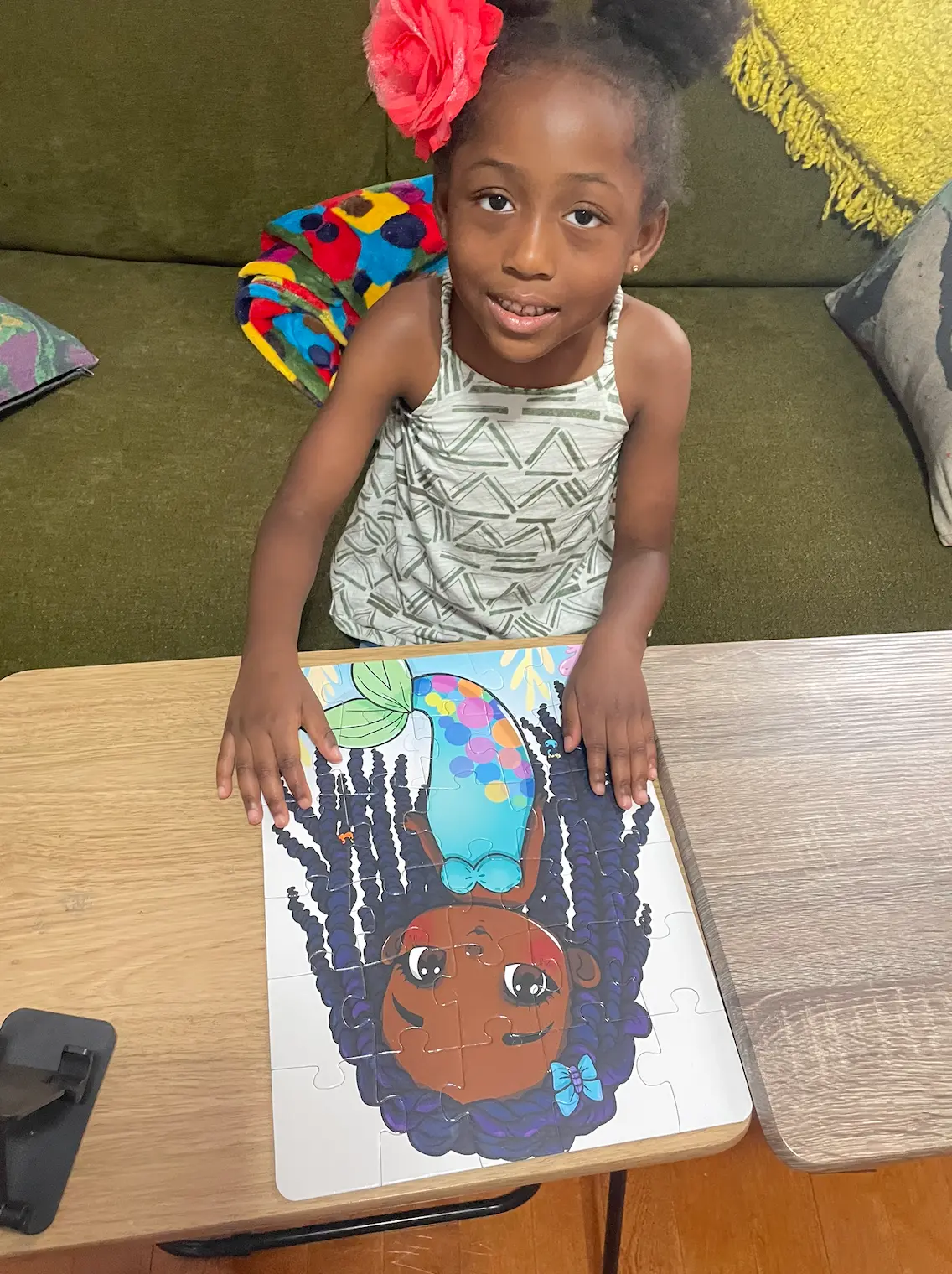 Augustine at a table with the finished original mermaid puzzle